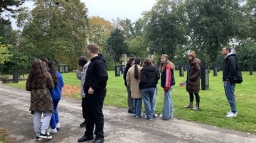 Foto einer Gruppe von Schülerinnen und Schülern, die über einen Friedhof laufen.